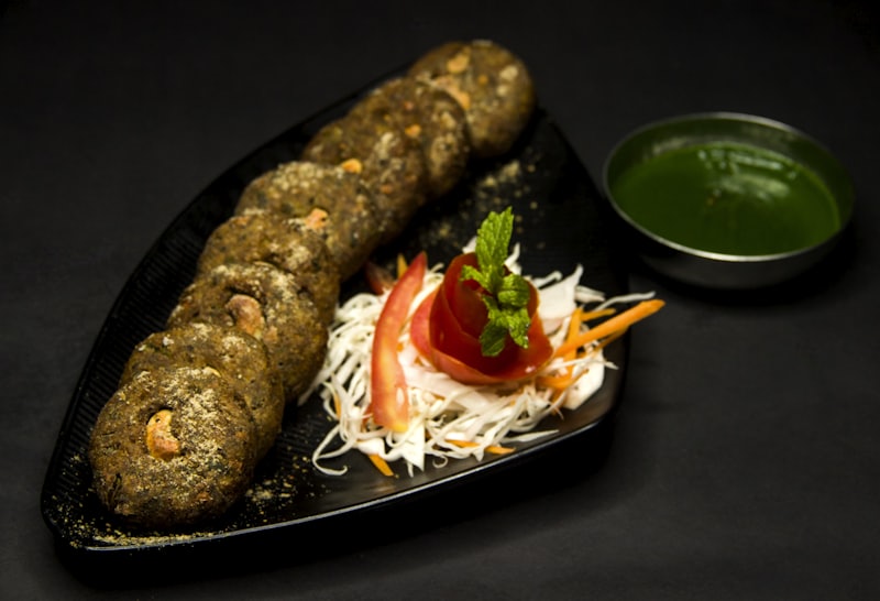 Seekh kebab with salad on a black plate